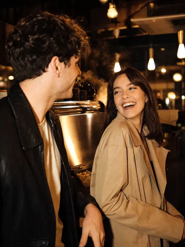 A man making a woman laugh at a coffee shop counter