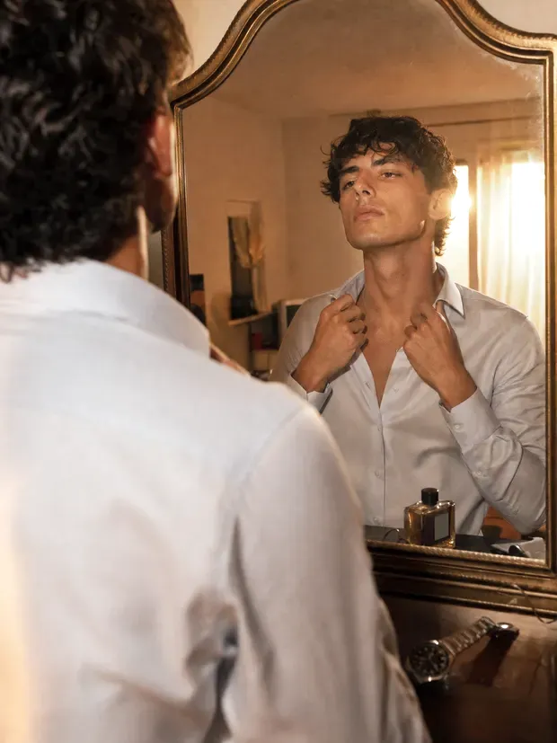 Man adjusting his collar in a mirror before a date